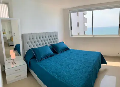 a bedroom with a blue bed and a window at 2 Bedroom Beachfront Apartment 2P1-Al2 With Pool And WIFI in Cartagena de Indias