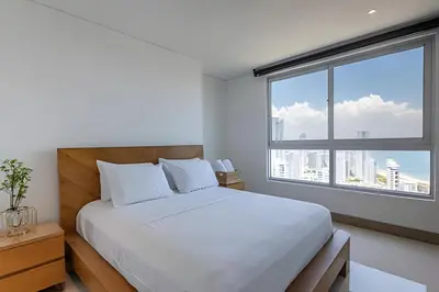 a bedroom with a white bed and a large window at Laurdhomes Palmetto Beach Floor 32, Sea View, 3HBT in Cartagena de Indias