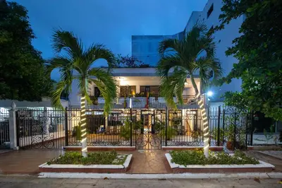a fence with two palm trees in front of a building at Hotel Boutique Casa Pere in Cartagena de Indias