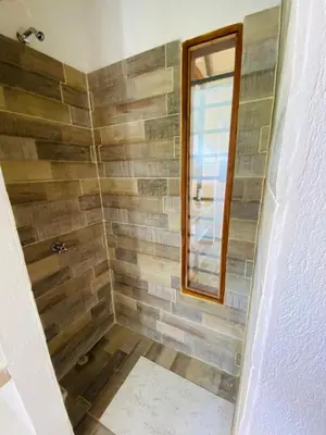 a bathroom with a walk in shower with a window at Cabaña cerca al Mar con Pisicina y AC en Tolú in Tolú