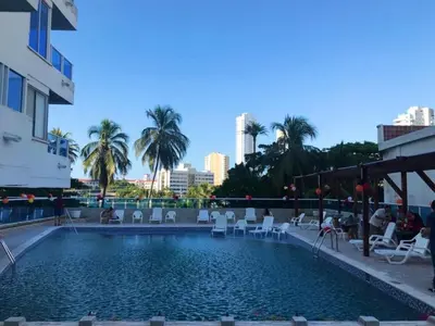 a swimming pool with chairs and palm trees and a city at Relax y Confort - Apartamento frente al Mar in Cartagena de Indias