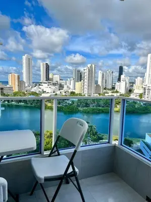 a chair on a balcony with a view of the city at Relax y Confort - Apartamento frente al Mar in Cartagena de Indias