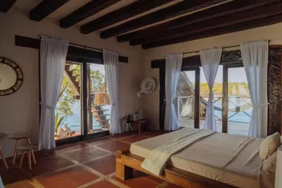 a bedroom with a bed and large windows at Isla Kalua - Private Ocean Villa in Isla Pavitos