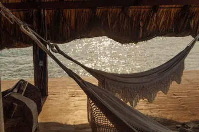 a hammock hanging from a building next to the water at Isla Kalua - Private Ocean Villa in Isla Pavitos