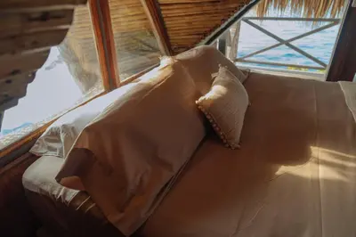 a couch with pillows on it in front of a window at Isla Kalua - Private Ocean Villa in Isla Pavitos
