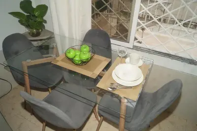 a glass dining table with chairs and a bowl of green balls at Apartamento el Calamar in Cartagena de Indias