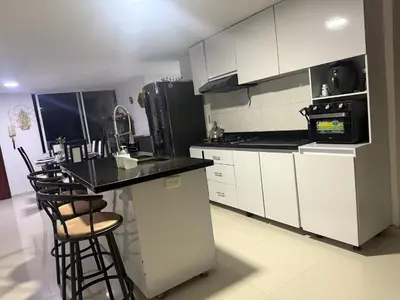 a kitchen with white cabinets and a black counter top at Lindos apartamentos in Cartagena de Indias