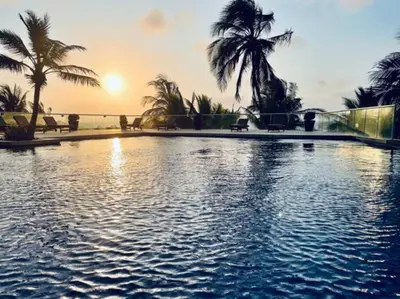 a large swimming pool with palm trees and the sunset at Cartagena- Apto con acceso y vista al mar Morros Ultra in Cartagena de Indias