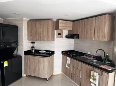 a kitchen with wooden cabinets and a black refrigerator at Vista a la Playa del Cabrero in Cartagena de Indias