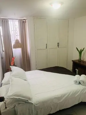 a bedroom with a large bed with white sheets and towels at Habitación en apartamento compartido al frente del cc Unico in Barranquilla