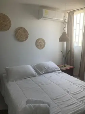 a white bed in a bedroom with a window at Habitación en apartamento compartido al frente del cc Unico in Barranquilla
