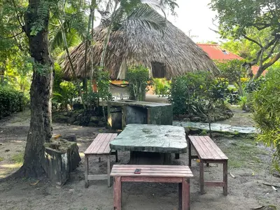 a picnic table and benches in front of a hut at Casa Santa María in El Porvenir