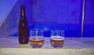 two glasses of beer and a bottle on a table at Casa Acogedora con Piscina - House Rouse 14 in Cartagena de Indias