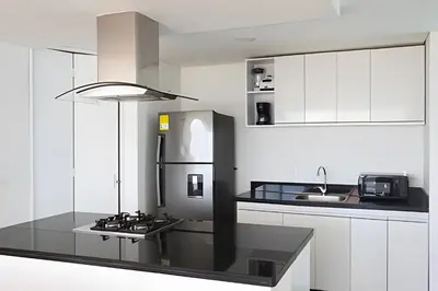 a kitchen with white cabinets and a black counter top at 2 dormitorios Morros. Hidromasaje y Vistas in Cartagena de Indias