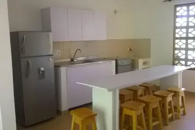 a kitchen with a counter and a refrigerator and stools at Apartamento frente al mar mejor playa en Coveñas in Coveñas