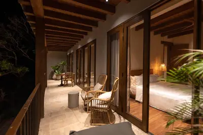 a bedroom with a bed and chairs on a balcony at Makani Luxury Cartagena in Tierra Bomba
