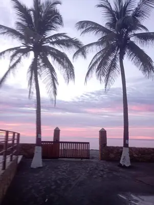 two palm trees on the beach with a sunset at NAHIR apartamento de playa en condominio Palmar del viento in San Bernardo del Viento
