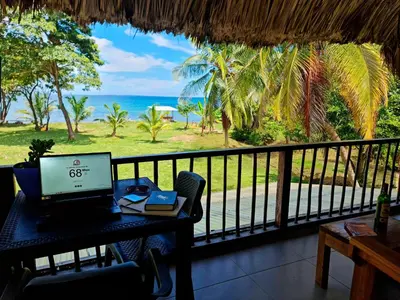 a desk with a laptop on a balcony with the ocean at Deluxe Family Suite - In front of the sea in Moñitos