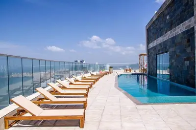 a row of lounge chairs next to a swimming pool at Apartamento 3404 Palmetto Beach Frente a la playa in Cartagena de Indias