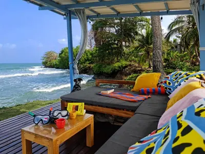 a porch with a couch and a table and the ocean at Beach House with AC Surrounded by Nature in Moñitos