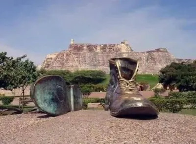 a statue of a boot sitting on the ground in front of a mountain at MoraRoom in Cartagena de Indias