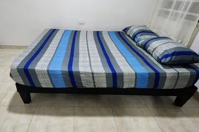 a bed with blue and white striped sheets and pillows at Lindo Apartamento cerca al Estadio Metropolitano in Barranquilla