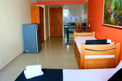 a room with two beds and a refrigerator at Studio Apartment E11C Near The Sea With Pool in Cartagena de Indias
