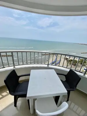 a white table and chairs on a balcony with the beach at Apartment al-1 facing the sea with pool and Wifi in Cartagena de Indias