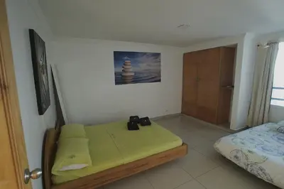 a small room with a bed and a bed and a door at Apartamentos Bacanos in Cartagena de Indias