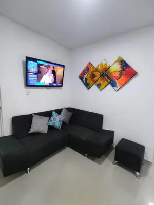 a living room with a black couch and a flat screen tv at Hermoso Apartamento en Caribe Campestre in Coveñas