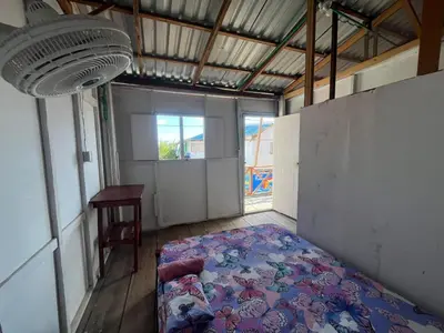 a bedroom with a bed and a table and window at Hostal Paraiso in Isla Mucura