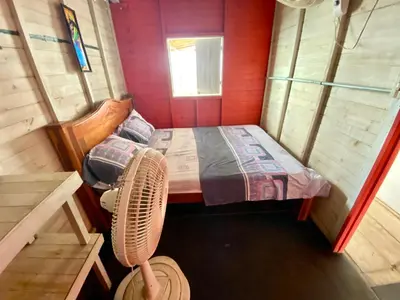 a small room with a bed and a fan at Hostal Paraiso in Isla Mucura