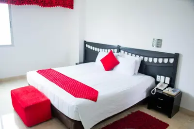 a bedroom with a large bed with red pillows at Hotel Suite Continental in Barranquilla