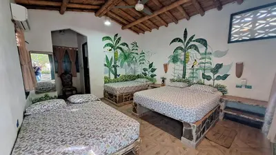 a bedroom with three beds and a mural on the wall at Eco-Hotel Chevere Beach in Puebloviejo