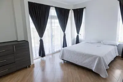a bedroom with a bed and a dresser and large windows at Casa Mandalay hotel in Juan de Acosta