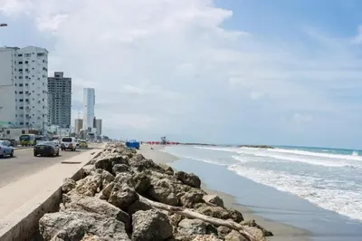 a beach with rocks and the ocean and buildings at Apartamento Marbella - En Edificio Frente a la Playa cerca al centro Histórico in Cartagena de Indias
