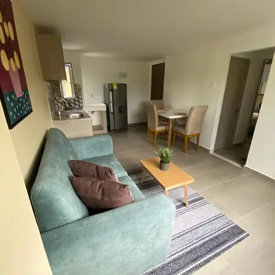 a living room with a blue couch and a table at Aparta Suites Balcones de la Sierra in Fundación