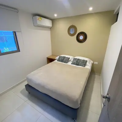 a bedroom with a bed and a clock on the wall at Aparta Suites Balcones de la Sierra in Fundación