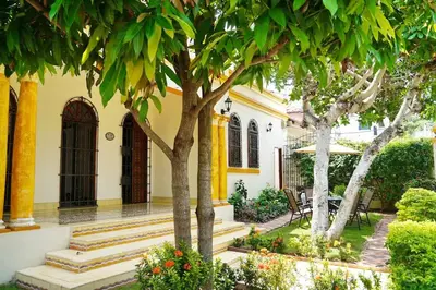 a house with trees and stairs in a yard at Casa Blanca María Barranquilla - Authentic republican house in Barranquilla