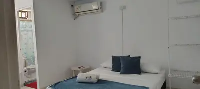 a small white room with a bed with blue pillows at Guacamayas in Santa Marta