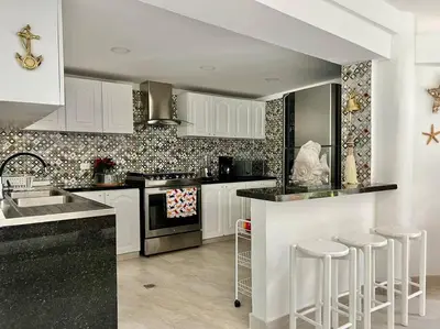 a kitchen with white cabinets and black counter tops at Casa El Faro, Hermosa casa de playa in Cartagena de Indias