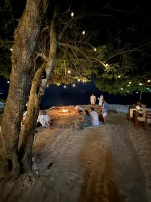 a group of people sitting around a fire on the beach at night at Thani Ecobeach Barú in Playa Blanca