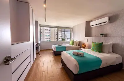 a hotel room with two beds and a television at U-GO Edificio Faro en El Laguito, Cartagena in Cartagena de Indias