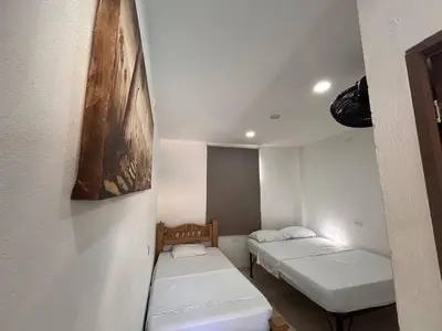 a room with two beds and a painting on the wall at Hostal Los Arhuacos in Santa Marta
