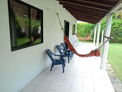 a porch with two chairs and a hammock on it at Mágica Cabaña familiar cerca al mar in Coveñas