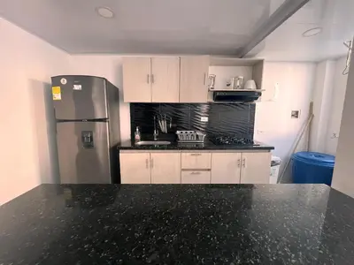a kitchen with a refrigerator and a black counter top at Hermoso apartamento en Coveñas con piscina in Coveñitas