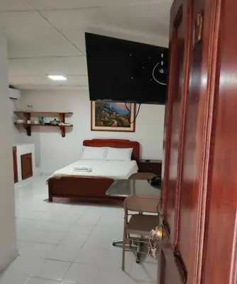a bedroom with a bed and a desk and a tv at Cecil Aparta Estudios in Barranquilla