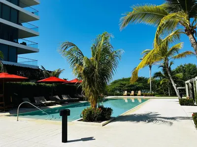 a swimming pool with palm trees and a building at Fantastic Apartment/Beach Front Luxury in Cartagena de Indias