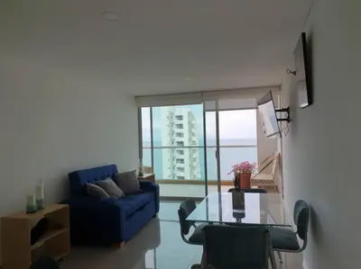 a living room with a blue couch and a glass table at Apartamento con vista al mar y al centro de Cartagena in Cartagena de Indias