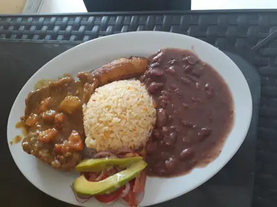 a plate of food with rice and beans and meat at Hotel Granada Inn in Barranquilla